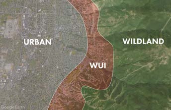 An aerial or satellite map showing the wildland-urban interface (WUI), which appears as a brown transitional zone between dense urban development on the left and natural wildland vegetation on the right. The image clearly labels three distinct areas: the gray urban zone with visible street grids, the brown WUI buffer zone in the middle, and the green wildland area covered in natural vegetation. This type of mapping is commonly used for wildfire risk assessment and urban planning purposes.
