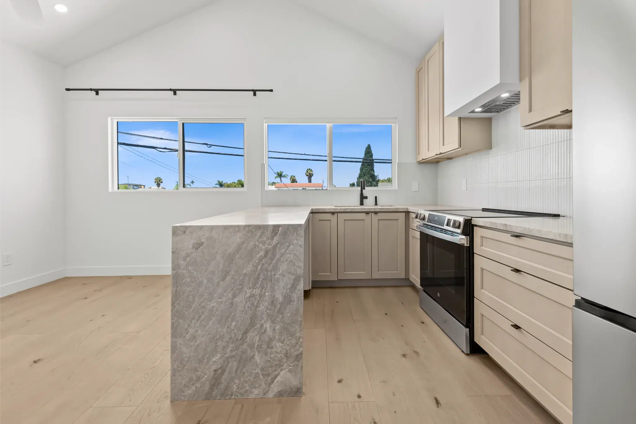 Bright remodeled kitchen with light wood cabinets and a waterfall-edge island, San Diego