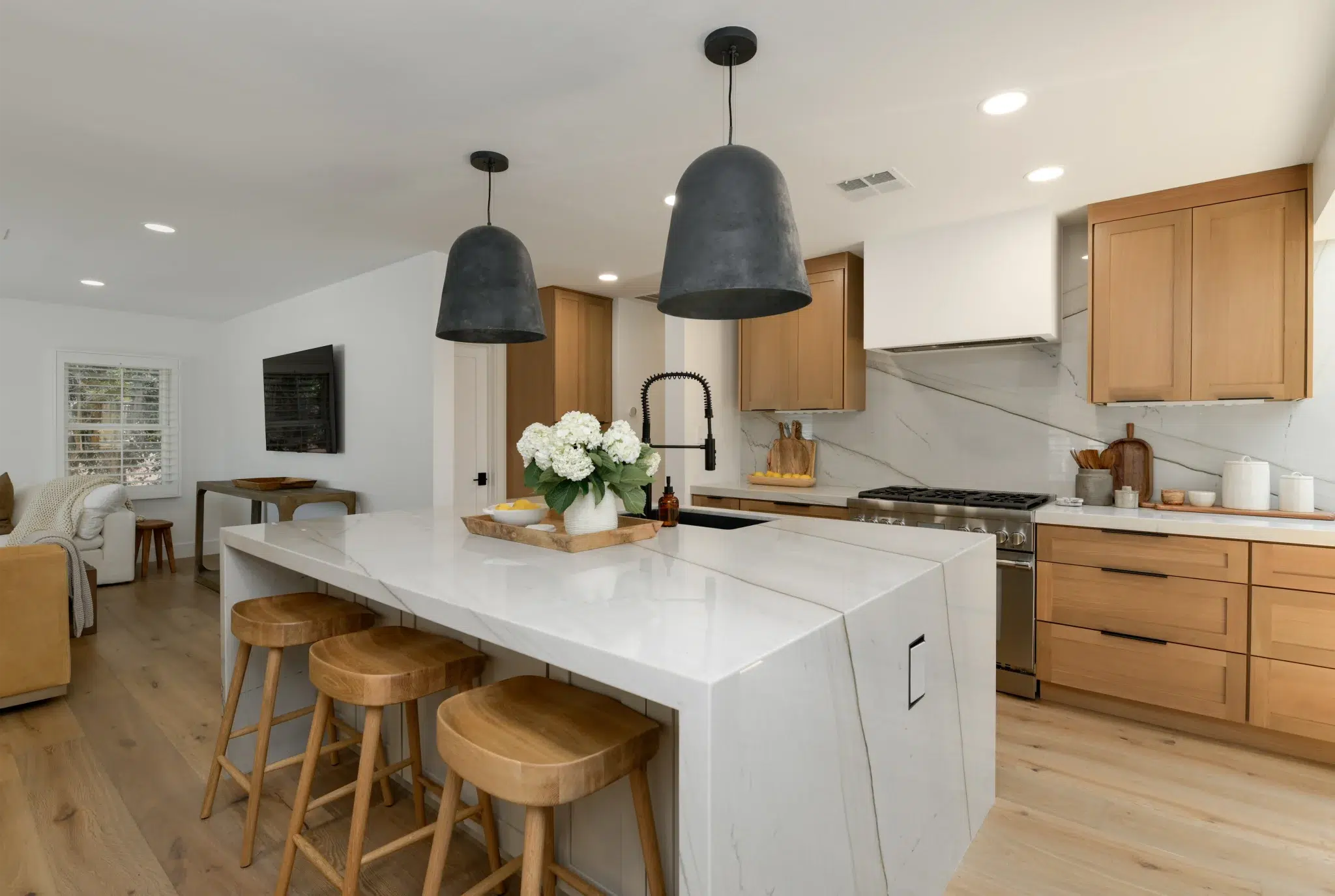 Waterfall quartz island with wood counter stools in an open kitchen, Wisteria Drive San Diego