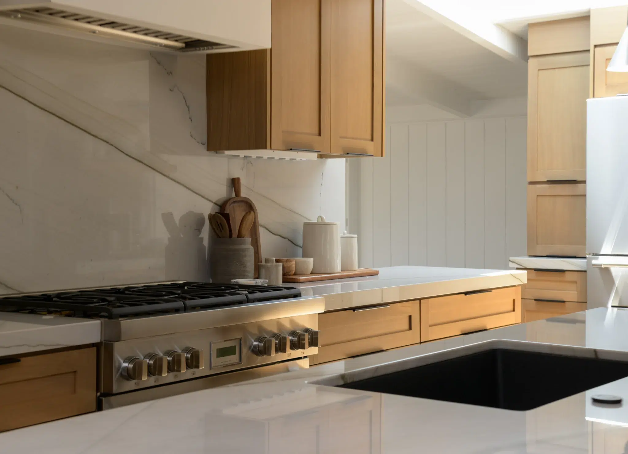 Professional gas range under a continuous quartz slab backsplash, San Diego kitchen